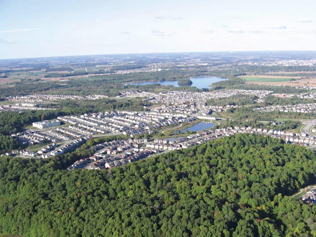 Report cover featuring Aerial photograph of suburban housing beside large forested areas and ponds.