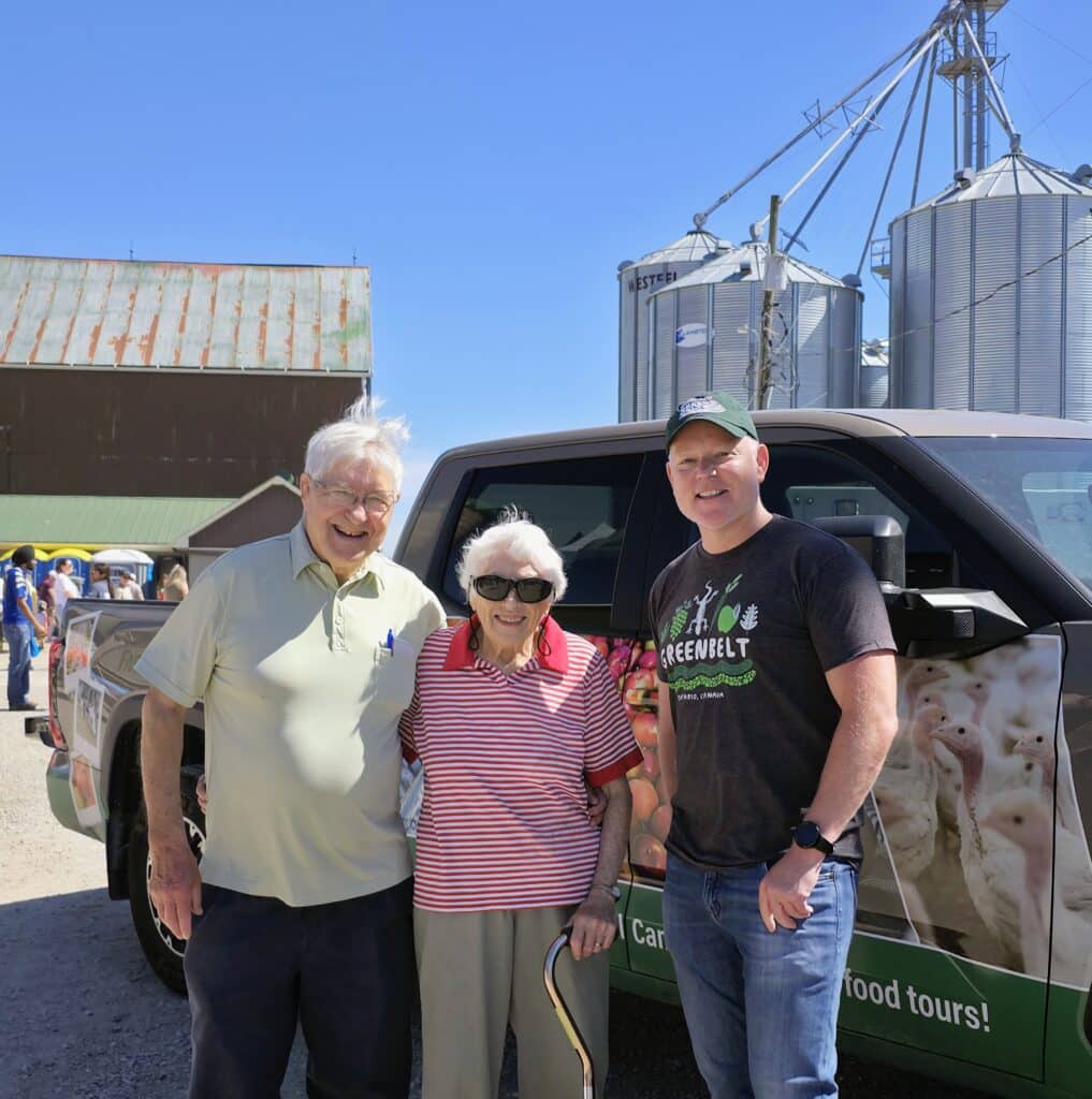 Three people smiling at a farm